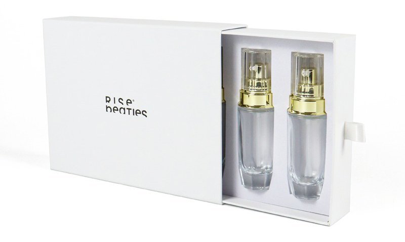 Open white double-door beauty gift box with 2 clear cosmetic spray bottles (gold pump tops) placed in custom inner tray