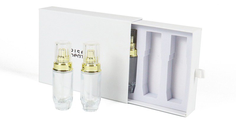 Partially unboxed white double-door beauty gift box – showing custom-fitted inner tray (with one cosmetic bottle remaining) for product protection